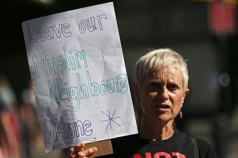 Eine Frau hält ein Schild in die Höhe mit der Aufschrift:
