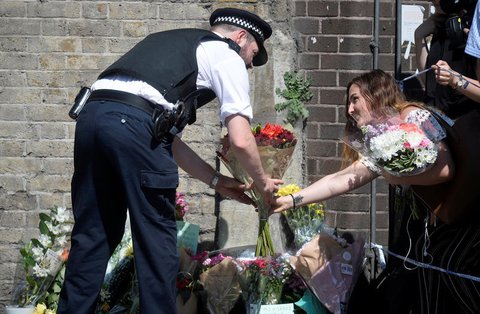 Ein Polizist hilft einer Frau in der Nähe des Anschlagsortes, Blumen abzulegen. Foto: REUTERS/Hannah McKay