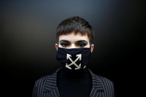 Ein Besucher der Modeschau mit Maske.