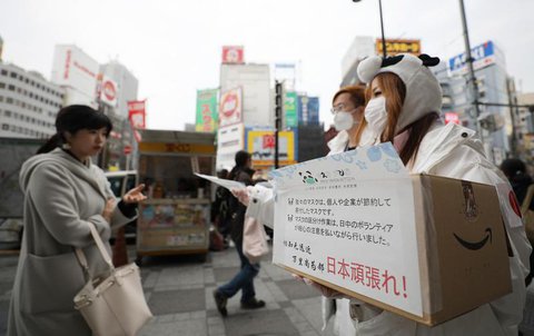 Freiwillige verteilen in Tokio Schutzmasken 