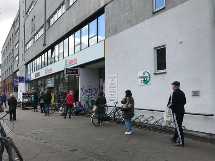 Schlage stehen vorm Supermarkt - mit Sicherheitsabstand.