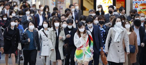 Dicht gedrängt, aber mit Mundschutz: Fußgänger in Tokio gehen über eine Straße.