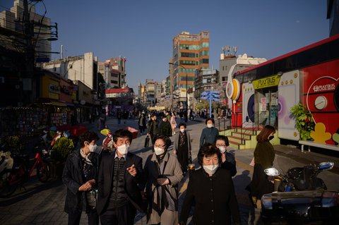 Menschen in Seoul tragen Schutzmasken während sie durch die Stadt laufen.