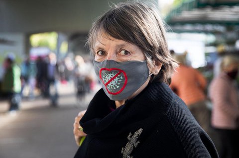 Eine Frau trägt einen Mund-Nasen-Schutz mit einem eingestickten Coronavirus.