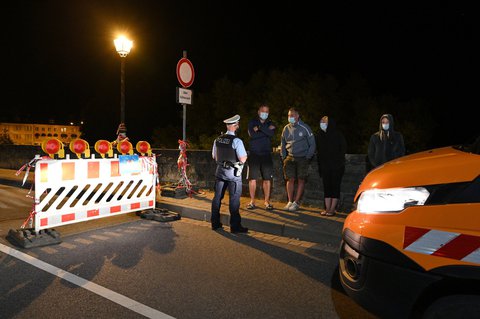 Ein Polizist spricht mit wartenden Grenzgängern an der Grenze zu Luxemburg. 