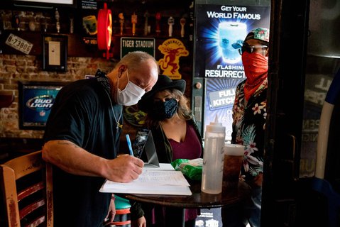 Ein Mitarbeiter nimmt die Kundendaten von zwei Gästen in einer Bar in New Orleans auf.