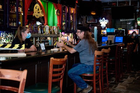 Eine Barkeeperin steht mit Mundschutz in der 