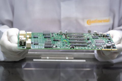 Eine Continental-Mitarbeiterin überprüft eine Platine für ein Fahrzeug-Steuergerät. 