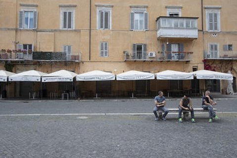 Drei Männer sitzen vor einem geschlossenen Restaurant.
