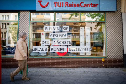 Eine Passantin mit Mund-Nasenschutz geht an einem Reisebüro vorbei.