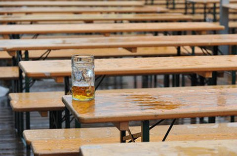 Halbleerer Maßkrug auf einer Bierbank
