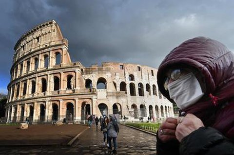 Mann mit Mund-Nasenschutz vor dem Colosseum in Rom