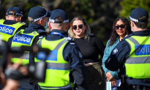 Polizisten sanktionieren zwei Frauen in Melbourne, die in der Öffentlichkeit keine Maske tragen.