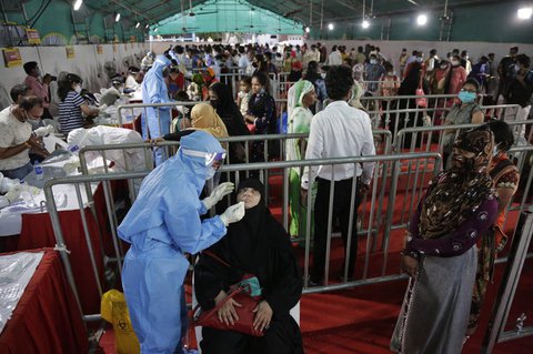 Ein Mitarbeiter des Gesundheitswesens entnimmt einen Nasenabstrich in 
einem Testzentrum an einem Bahnhof in Ahmedabad.