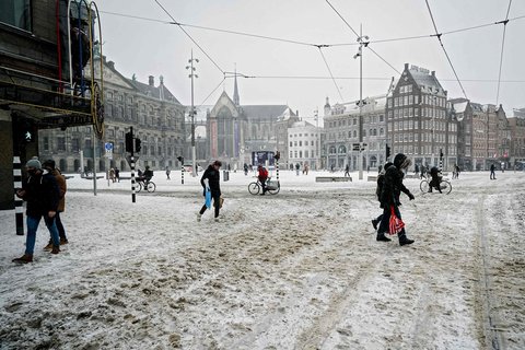Menschen laufen am Sonntag durch die schneebedeckten Straßen in Amsterdam.