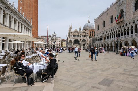 Die Menschen sitzen an Tischen im Freien am Markusplatz, während Italien die Quarantänebeschränkungen für Reisende aus Ländern der Europäischen Union, Großbritannien und Israel aufhebt und Corona-freie Flüge anbietet, um die Tourismusbranche in Venedig, Italien, wiederzubeleben.