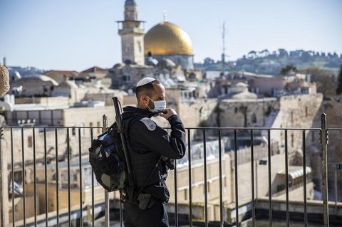 Ein israelischer Polizist mit Mundschutz steht in der Altstadt Wache, im
Hintergrund der Felsendom auf demTempelberg.