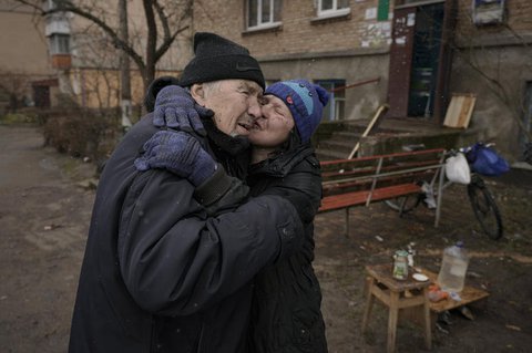 Eine Frau küsst einen Mann, während sie auf einem offenen Feuer vor einem 
Wohnhaus kocht, das seit Beginn der russischen Invasion in Butscha, Ukraine, ohne Strom, Wasser und Gas ist. 