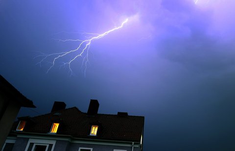 Ein Blitz ist in Unterfranken über einem Wohnhaus zu sehen.