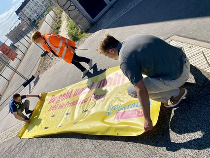 Die jungen Liberalen rollen ihr Transparent wieder zusammen.