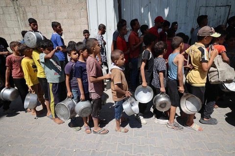 Palästinensische Kinder warten an einer Feldküche in Nuseirat auf die Essensausgabe. 