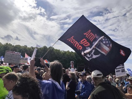Ein Demoteilnehmer hat eine Flagge des rechtsextremen Compact-Magazins dabei.