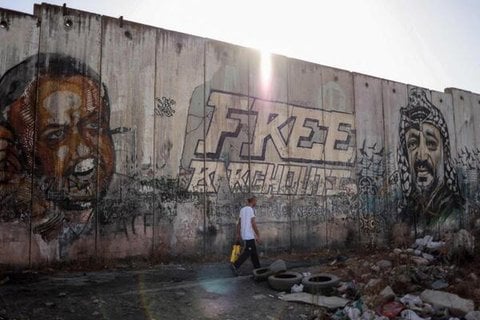 Ein Mann geht im Westjordanland an Porträts des führenden Mitglieds der Fatah-Partei Marwan Barghouti (links), dem bekanntesten palästinensischen Häftling in israelischer Haft, und des verstorbenen palästinensischen Führers Yasser Arafat (rechts) vorbei (Symbolbild).