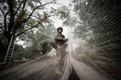 Ein Soldat der 24. Mechanisierten Brigade der ukrainischen Streitkräfte, installiert in der Frontstadt Kostiantynivka in der Region Donezk Anti-Drohnen-Netze über einer Straße.