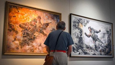 Ein Besucher betrachtet Gemälde in einer nordkoreanischen Kunstausstellung in Moskau.