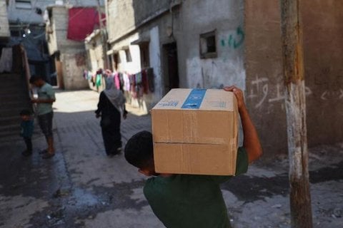 Ein palästinensischer Junge trägt eine Kiste mit Hilfsgütern des Welternährungsprogramms (WFP), die er am 19. Oktober 2025 an einer Hilfsgüterausgabestelle im Flüchtlingslager Nuseirat im zentralen Gazastreifen erhalten hat (Archivbild).