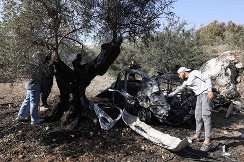 Palästinenser betrachten die Trümmer eines Fahrzeugs an der Stelle, an der drei Palästinenser bei einem Überfall israelischer Streitkräfte im Dorf Kafr Qud in der Nähe der von Israel besetzten Stadt Jenin im Westjordanland am 28. Oktober 2025 getötet wurden.