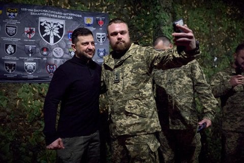 Der ukrainische Präsident Wolodymyr Selenskyj posiert für ein Foto mit einem Soldaten.
