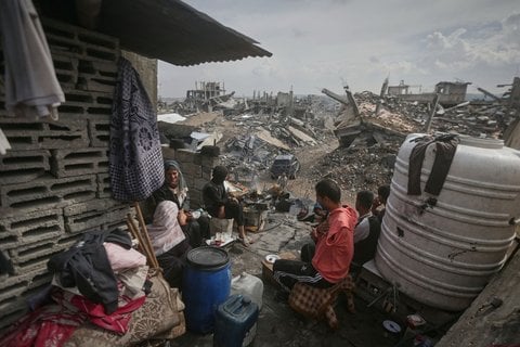 Die Familie Atallah sitzt vor ihrem beschädigten Haus in Gaza, umgeben von den Trümmern benachbarter Häuser.