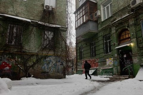 Ein Mann geht am 8. Januar 2026 an Wohngebäuden auf einer schneebedeckten Straße in Kiew vorbei (Symbolbild).