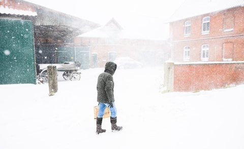 Ein Mann geht beim Schneesturm an einem Hof in der Region Hannover vorbei.