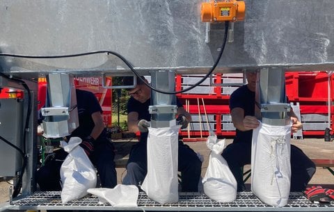 Mitarbeiter der Berufsfeuerwehr Flensburg füllen Säcke mit Sand. 