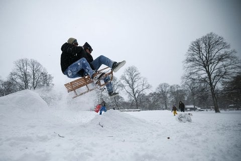 Schlittenfahrer im tief verschneiten Schanzenpark.