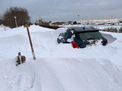 Auf der niedersächsischen Insel ist ein Auto zur Hälfte von Schnee bedeckt.