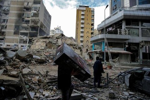 Eine Person trägt eine Schachtel mit Computerspielen, die sie aus ihrer zerstörten Wohnung nach den israelischen Luftangriffen auf den südlichen Vorort von Beirut,