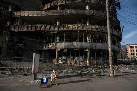 Ein Junge spielt vor einem zerstörten Einkaufszentrum in Kyjiw Akkordeon.